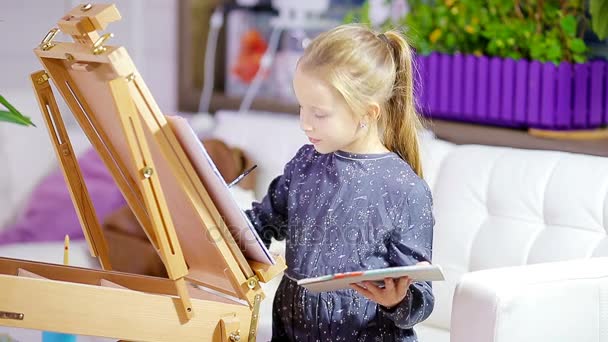 Schattig klein meisje schilderen een beeld op ezel indoor — Stockvideo