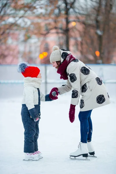 Маленька чарівна дівчинка з мамою катається на ковзанах на льоду — стокове фото