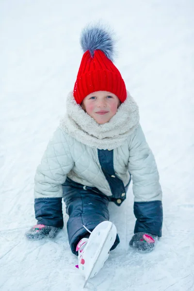 Petite adorable fille assise sur la glace avec des patins après l'automne — Photo