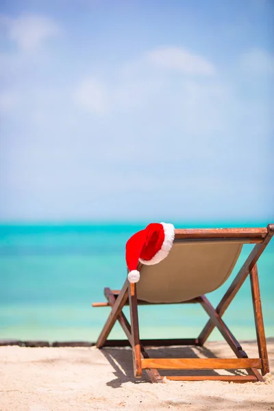 Natale in spiaggia - sedia con cappelli di Babbo Natale in mare. Natale concetto di vacanza — Foto Stock