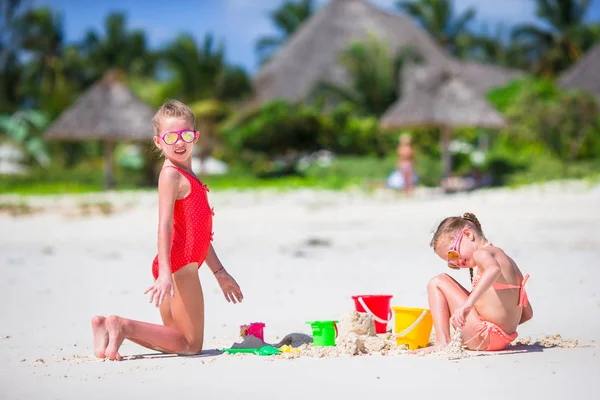 Schattige kleine meisjes tijdens de zomervakantie. Kinderen spelen met strand speelgoed op het witte strand — Stockfoto