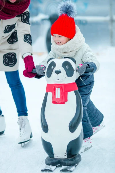 Pequena menina adorável aprendendo a patinar na pista de gelo ao ar livre — Fotografia de Stock