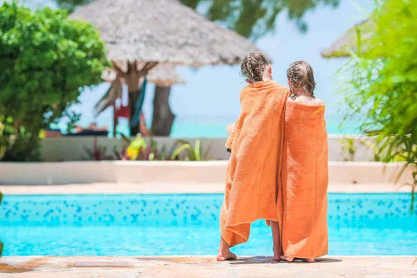 Adoráveis meninas embrulhadas em toalha na borda da piscina — Fotografia de Stock