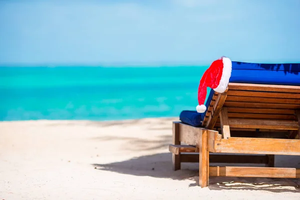 Jultomten hatt på beach solstol med turkosa havet vatten och vit sand. Christmas vacation koncept — Stockfoto