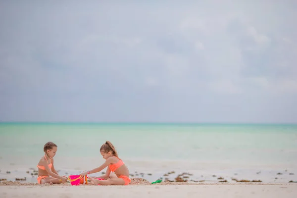 Bedårande små flickor leker med leksaker under strandsemester — Stockfoto