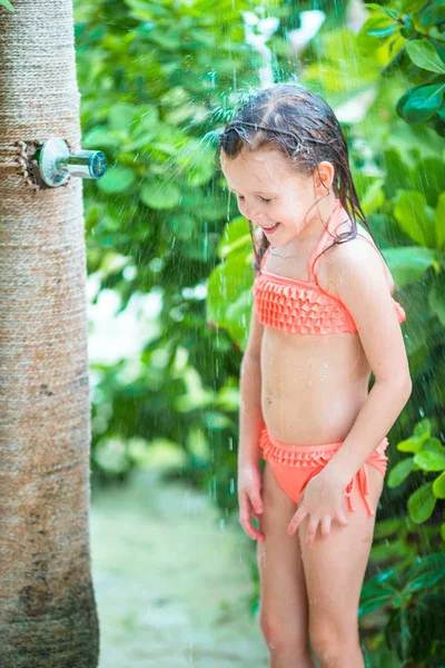 Liten, lykkelig jente under badedusjen på tropisk strand – stockfoto