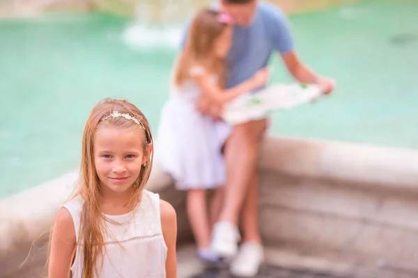 Familie mit touristischer Karte in der Nähe von fontana di trevi, rom, italien. Porträt eines kleinen Mädchens Hintergrund des Trevi-Brunnens. — Stockfoto