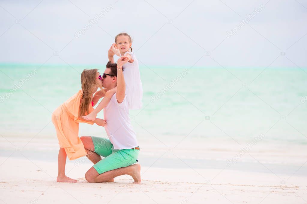 Young family enjoying beach summer vacation. Kids and dad find something on the sand