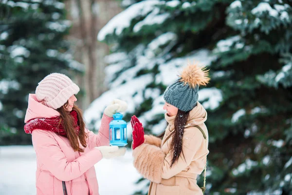 Junge Mädchen mit Weihnachtskerzenschein im Freien an einem schönen Winterschneetag und wärmen ihre Hände — Stockfoto