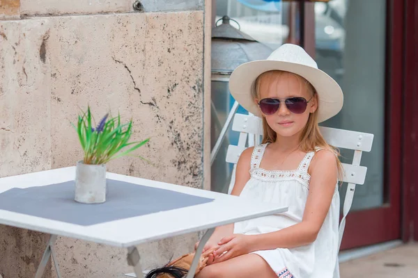 Klein meisje in outdoor cafe op warme zomerdag — Stockfoto