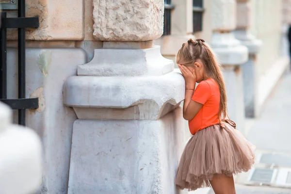 Malá dívka hraje na schovávanou na ulici v Evropě venku — Stock fotografie