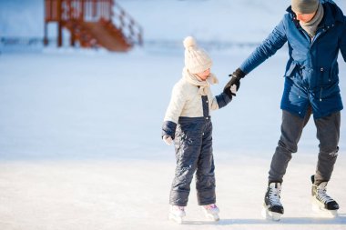 Genç Baba ve sevimli küçük kız açık havada buz pateni pisti üzerinde eğlenmek