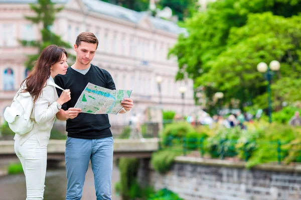 Pareja viajando en su luna de miel en Europa. Familia caucásica con mapa de la ciudad en busca de atracciones — Foto de Stock