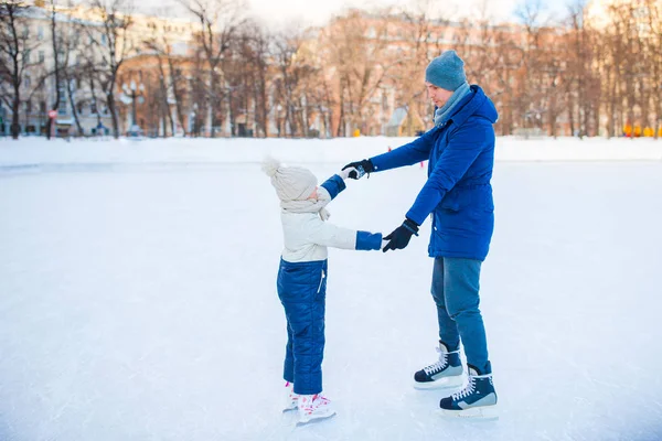 Młody ojciec i urocze dziewczynki mogą bawić się na lodowisko na zewnątrz — Zdjęcie stockowe