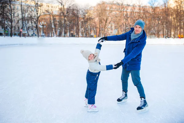 Niña aprendiendo a patinar con su padre en pista de hielo al aire libre — Foto de Stock