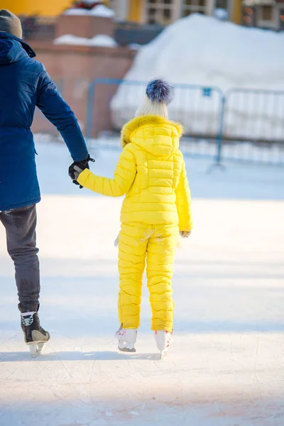 Mała dziewczynka uczenia się skate z ojcem na lodowisko na zewnątrz — Zdjęcie stockowe