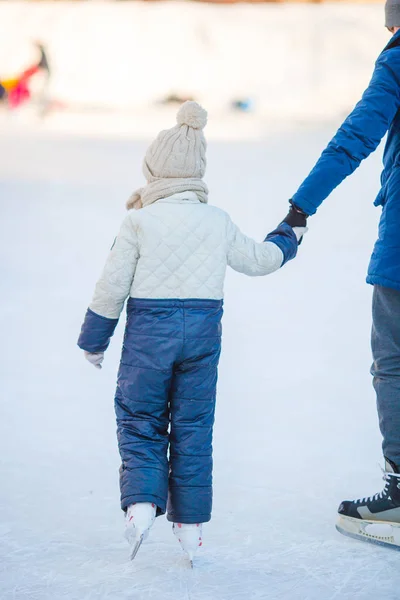 Kleines Mädchen lernt mit Vater Schlittschuhlaufen auf Eisbahn — Stockfoto