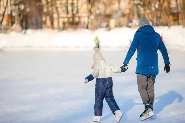 Kleines entzückendes Mädchen mit Vater lernt Schlittschuhlaufen auf der Eisbahn — Stockfoto