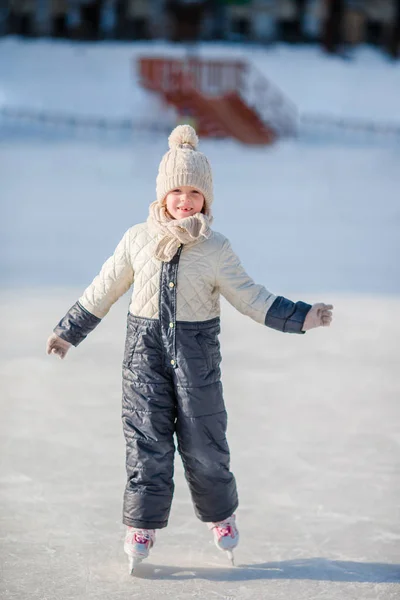 Entzückendes kleines Mädchen beim Schlittschuhlaufen auf der Eisbahn. — Stockfoto