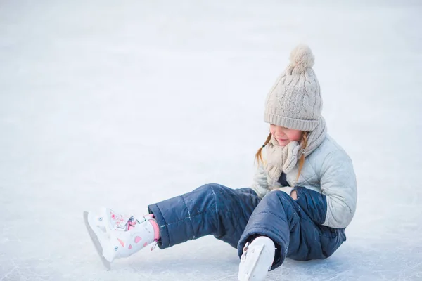 Niña adorable tumbada en el hielo con patines después del otoño —  Fotos de Stock