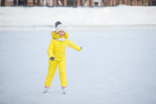 Adorabile bambina che pattina sulla pista di pattinaggio all'aperto nella calda giornata invernale — Foto Stock