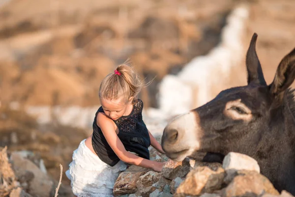 Маленькая девочка с ослом на острове Миконос — стоковое фото