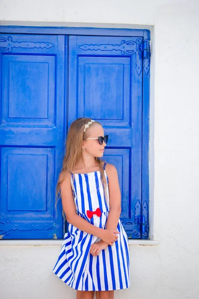 Adorable little girl in front of blue door outdoors at typical greek traditional village on Mykonos in Greece — Stock Photo, Image
