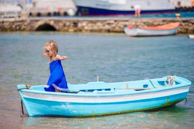 Yunanistan'da Mykonos yakınındaki defne deniz mavi tekne küçük kız. Küçük çocuk küçük tekne Yüzme keyfini çıkarın.