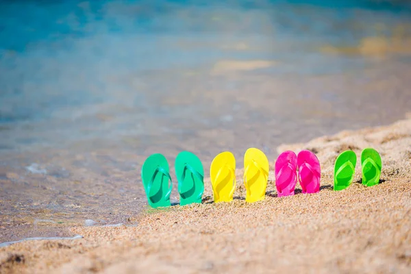 Family colorful flip flops on beach in front of the sea