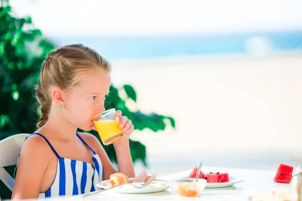 Entzückendes kleines Mädchen frühstückt im Café mit Meerblick — Stockfoto