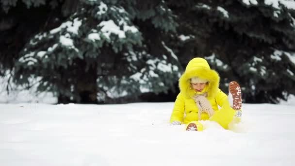 Чарівна маленька дівчинка в сніжну погоду на відкритому повітрі в красивий зимовий день — стокове відео