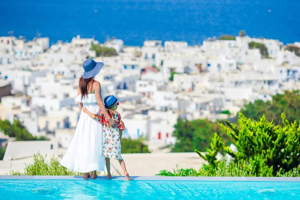 Adorable little girl and young mother in outdoor swimming pool background Mykonos town on Cyclades, Greece — Stock Photo, Image
