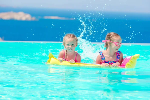 Adorable little girls playing in outdoor swimming pool with beautiful view — Stock Photo, Image