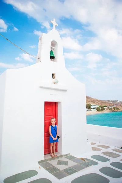 Schattig meisje in blauwe jurk buiten in de buurt van church. Kid op straat van typische Griekse traditionele dorp op het eiland Mykonos — Stockfoto