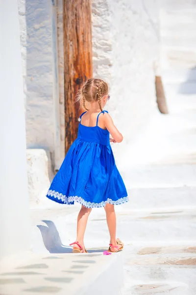 Adorable niña en la calle del típico pueblo tradicional griego en la isla de Mykonos, en Grecia —  Fotos de Stock