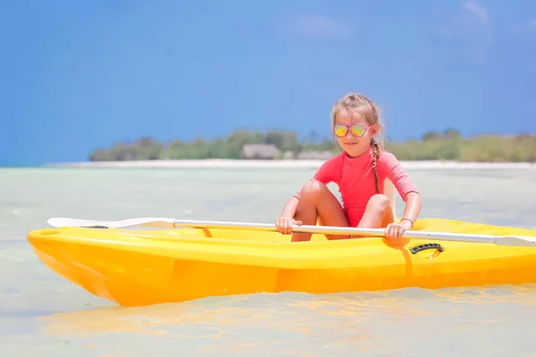 Adorable little girl kayaking during summer vacation