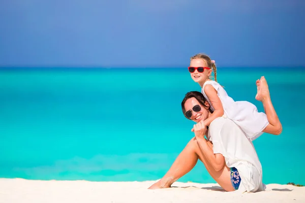 Liten söt flicka och ung mor på tropisk strand — Stockfoto