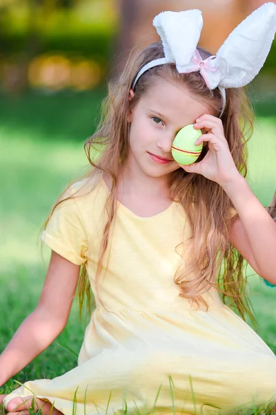 Adorable little girl wearing bunny ears with Easter eggs on spring day — Stock Photo, Image