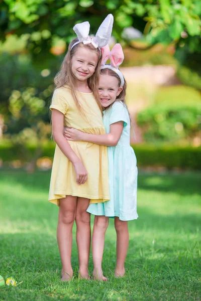 Two adorable little sisters wearing bunny ears on Easter day outdoors — Stock Photo, Image