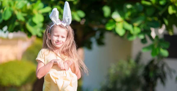Adorabile bambina che indossa orecchie di coniglio con uova di Pasqua il giorno di primavera — Foto Stock
