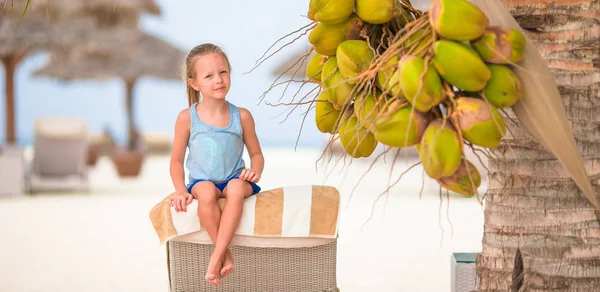 Little adorable girl near coconut on white tropical beach — Stock Photo, Image