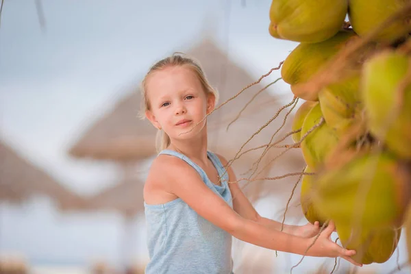 Little adorable girl near coconut on white tropical beach — Stock Photo, Image