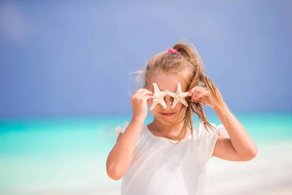 Adorabile bambina con stelle marine sulla spiaggia — Foto Stock