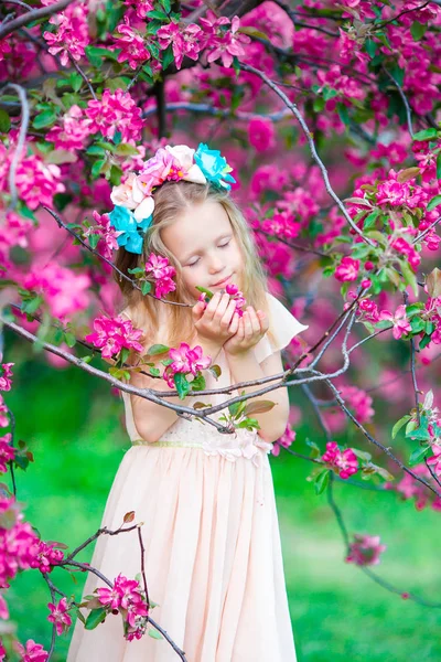 Очаровательная маленькая девочка наслаждается запахом в цветущем весеннем саду — стоковое фото