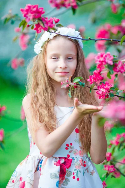 Adorable petite fille jouissant d'une odeur dans un jardin printanier fleuri — Photo