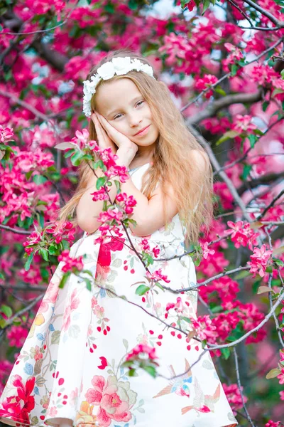 Adorable niña en el jardín de manzanos en flor en el día de primavera —  Fotos de Stock