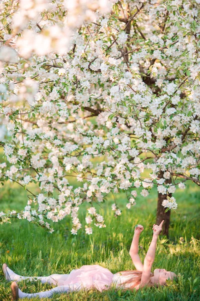 Adorable niña en el jardín de cerezo en flor en el día de primavera — Foto de Stock