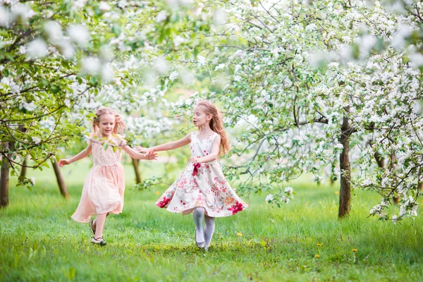 Beautiful girls in blooming apple tree garden enjoy warm spring day — Stock Photo, Image