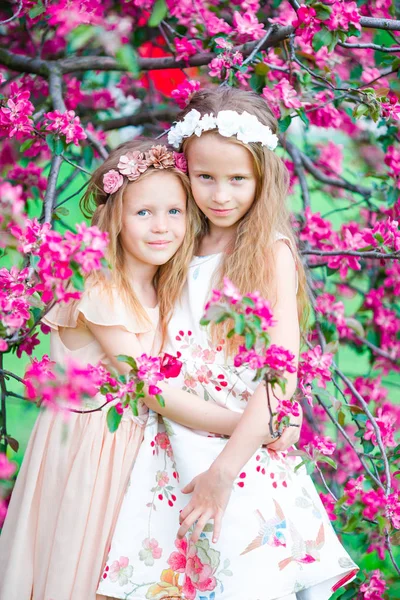 Adorable little girls in blooming apple tree garden on spring day — Stock Photo, Image