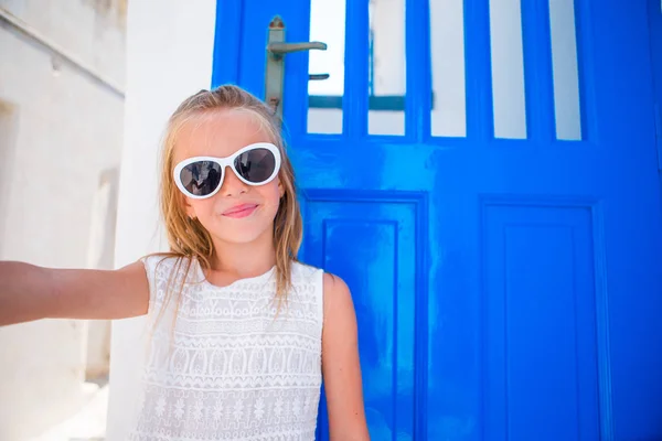 Niña adorable tomando autorretrato al aire libre fondo azul puerta en vacaciones griegas —  Fotos de Stock